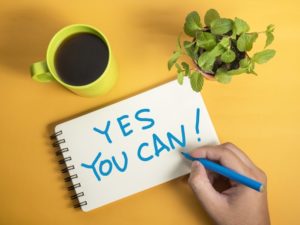 Yes You Can! written on notepad with a cup of coffee and plant by it's side